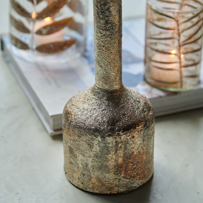 Rustic texture and aged metallic patina on candle holder.