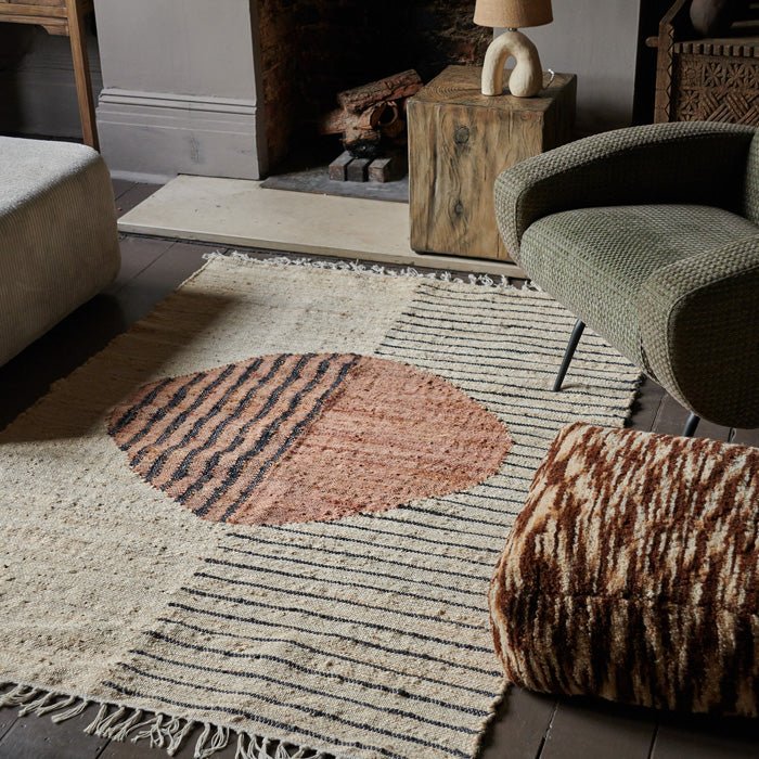 Large cream jute rug, with woven red circle in centre and black stripe design, finished with tasseled ends.