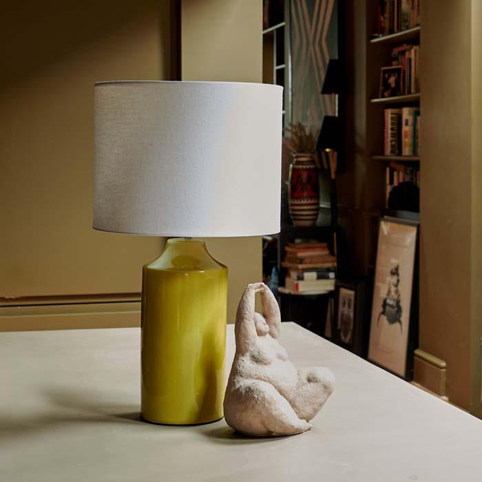 Lime green table lamp with a cream shade sat behind a female yoga sculpture