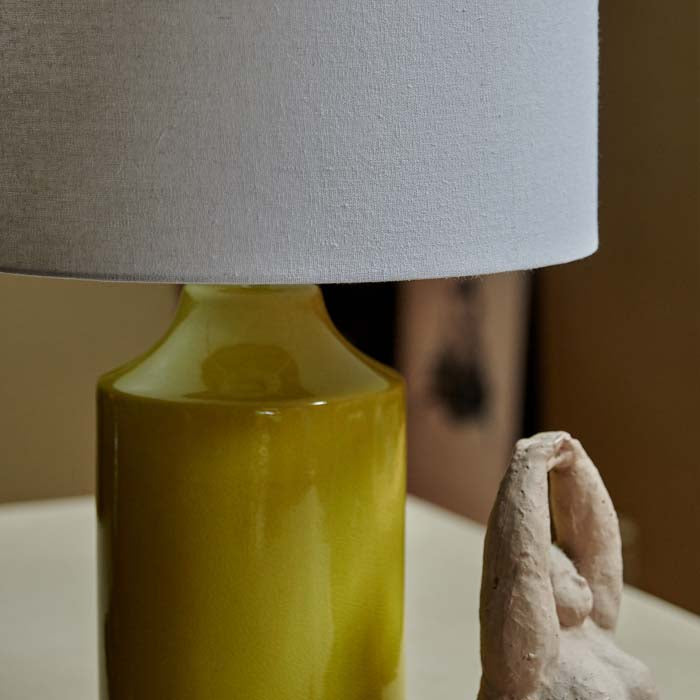 Lime green and cream table lamp with a figurative sculpture in front
