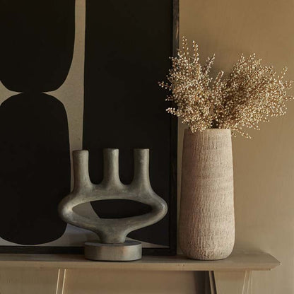 Textured grey vase in a cylindrical shape next to a dark grey candleholder