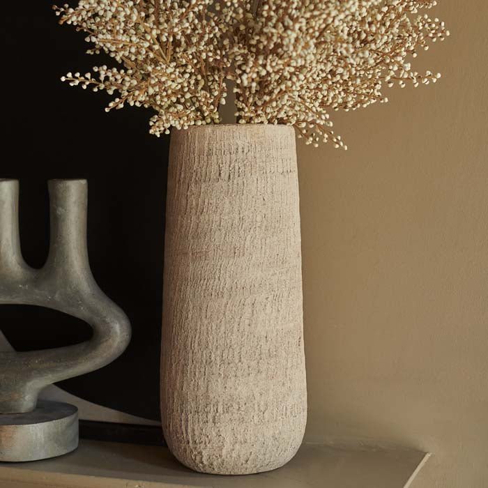 Tall grey textured vase in a cylindrical shape sat on a mantle
