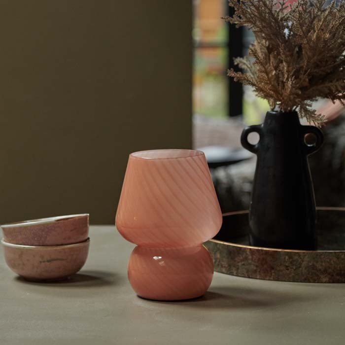 Mushroom shaped glass led lamp in a coral colour sat on a coffee table