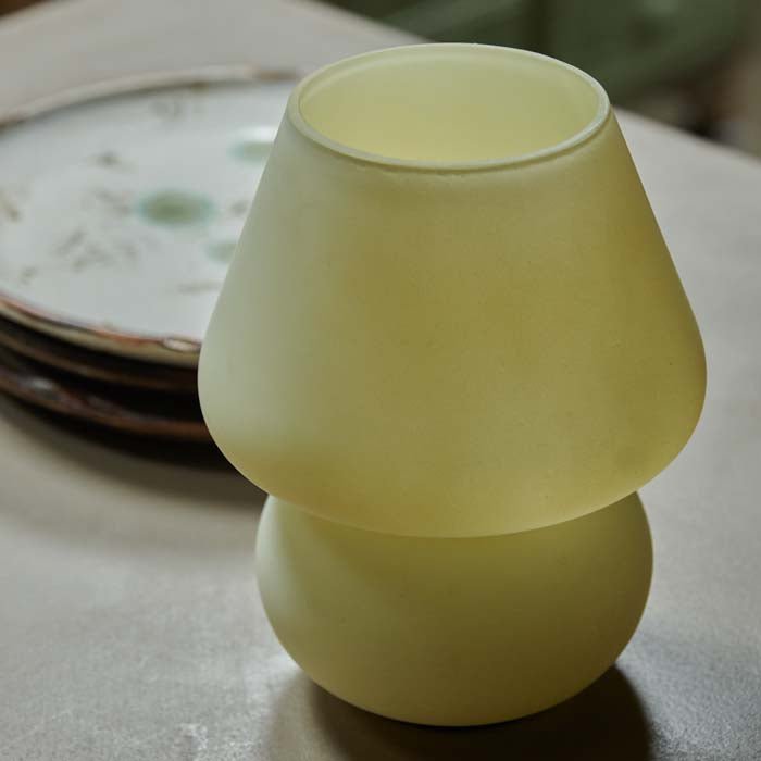 Frosted yellow LED lamp shaped like a mushroom on a wooden table