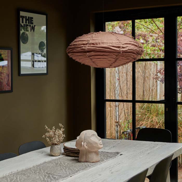 Oval shaped brown pendant shade hanging above a wooden dining table