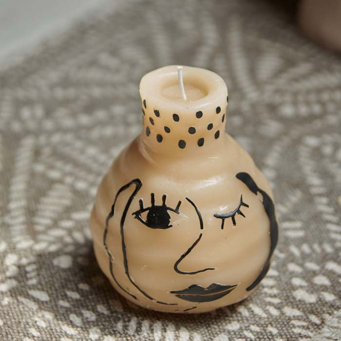 Curvy cream pillar candle with an abstract face painted on