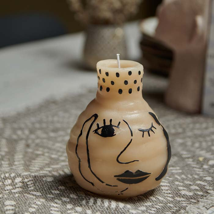 Cream pillar candle with an abstract face painted on its side