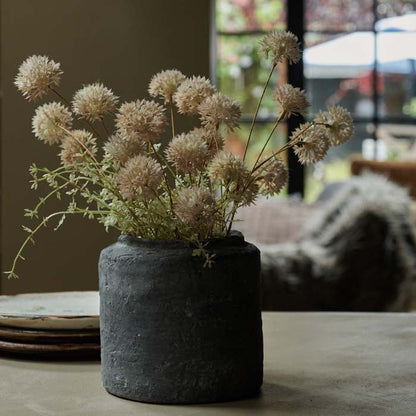Rustic grey cement vase with artificial meadow pompom flowers.