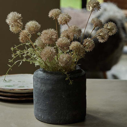 Artificial meadow flowers in a rustic grey cement vase.