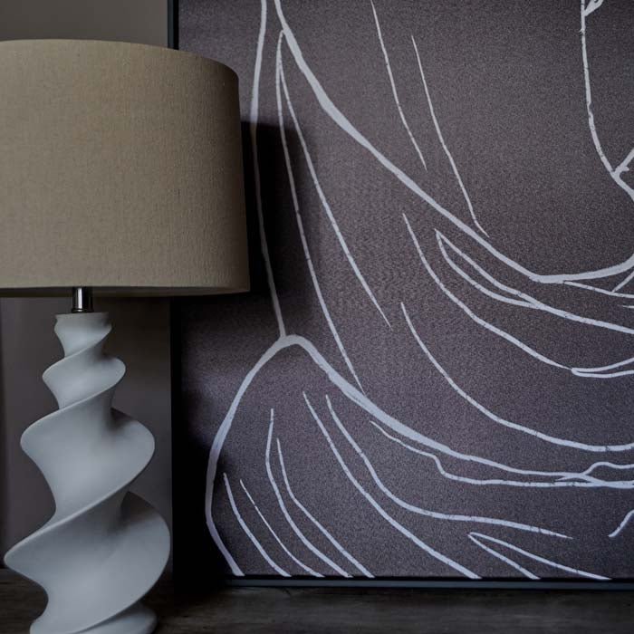 Black and white figurative print sat on a console table behind a white lamp