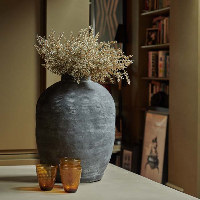 Artificial white flowers in a large grey cement vase on a kitchen island.