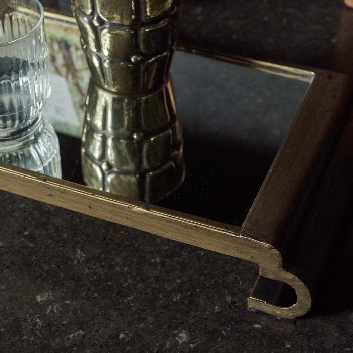 Gold pedestal tray with a mirrored surface sat on a black worktop