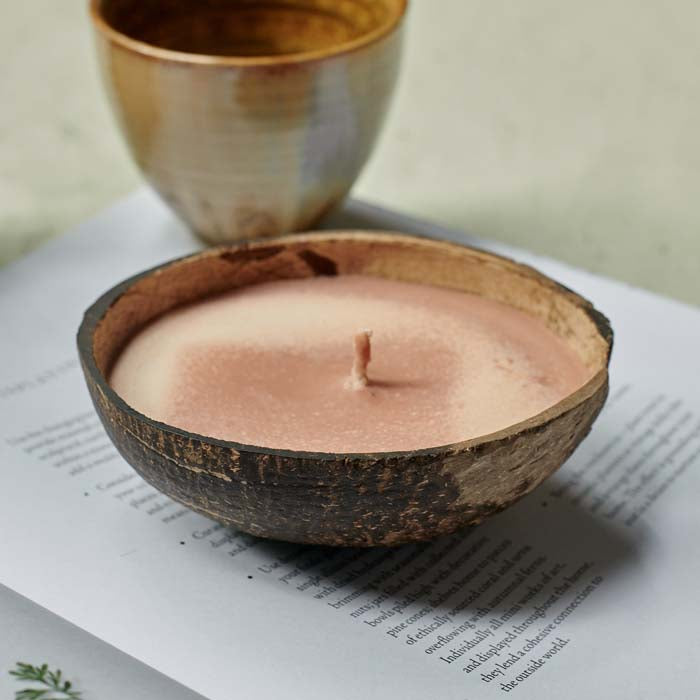 Orangey-pink coloured scented candle poured into a coconut shell