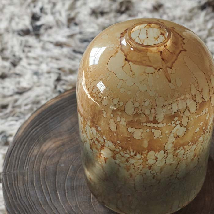 Curved amber patterned glass vase with a small opening on its top