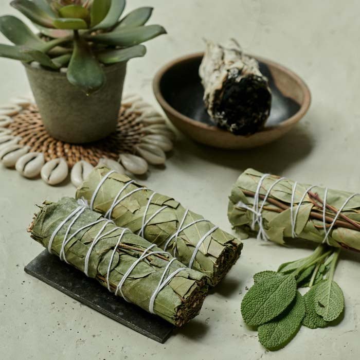 Three naturally dried eucalyptus smudge sticks resting on a creamy grey surface