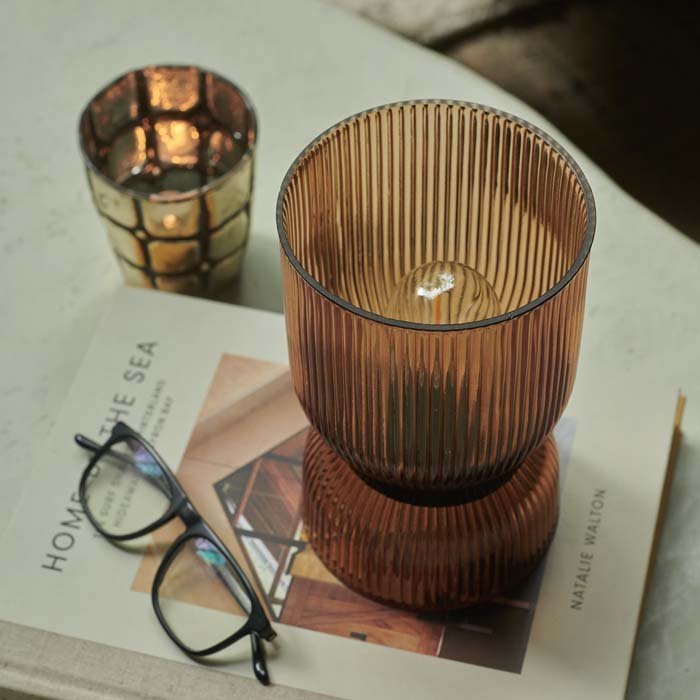 Cordless amber LED lamp in a ribbed texture sat on a magazine 