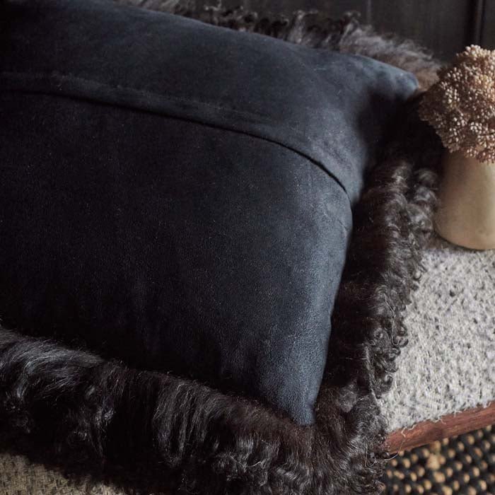 Soft, plain back of a black sheepskin cushion with a hidden zip
