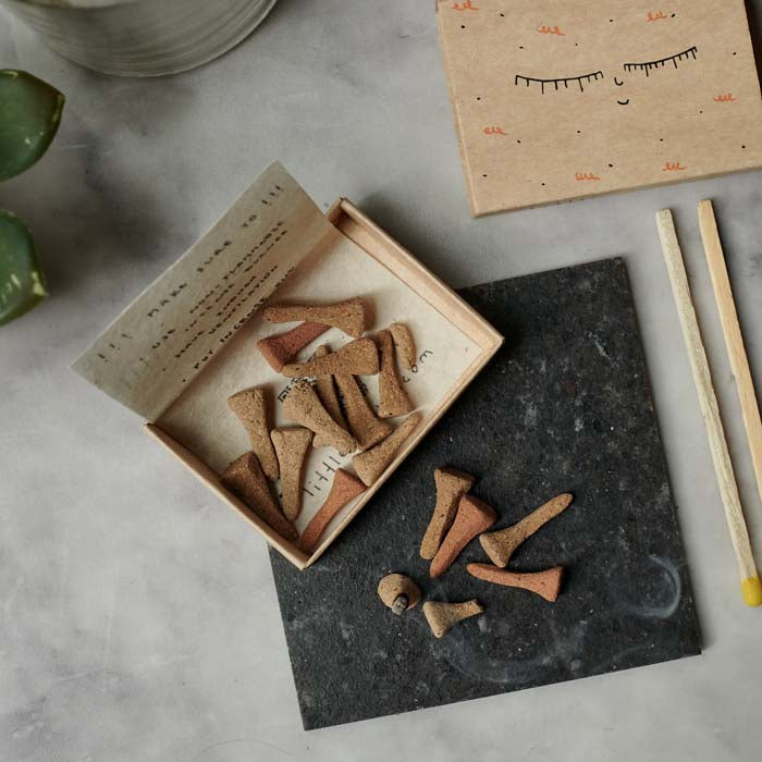 Small box of irregularly shaped cone incense sat on a slate tray