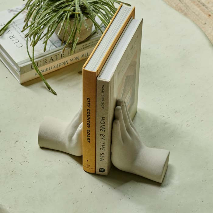Two cream hand shaped bookends at either end of two books