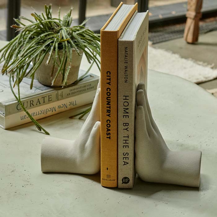 Two hand shaped bookends holding up two coffee table books