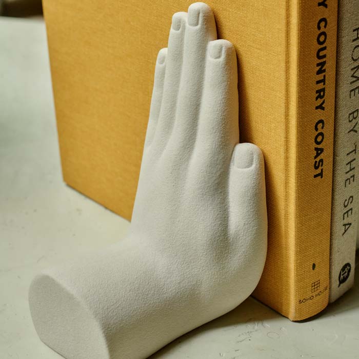 White hand shaped bookend holding up a yellow book