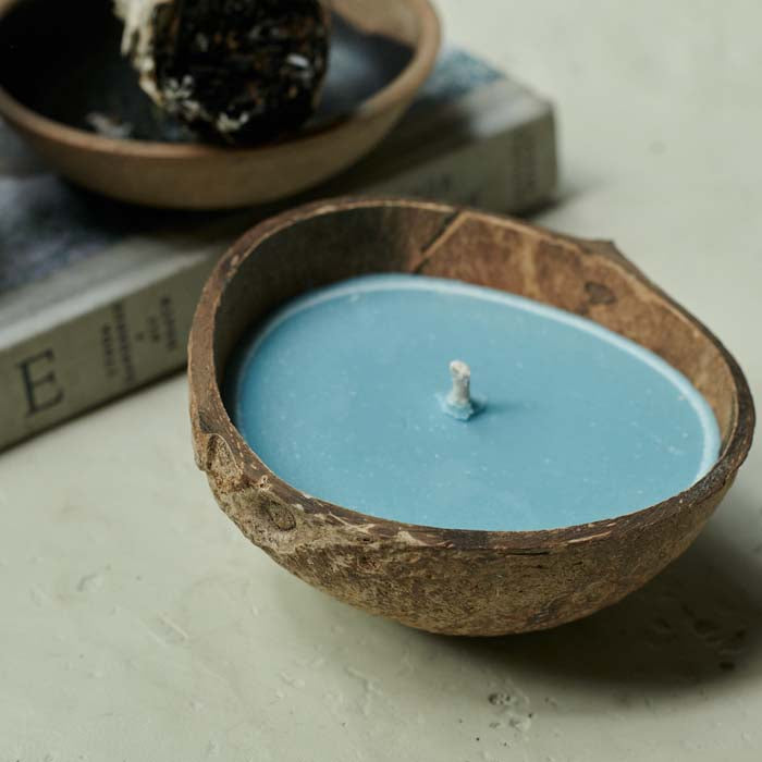 Blue coloured scented candle poured into half a coconut shell