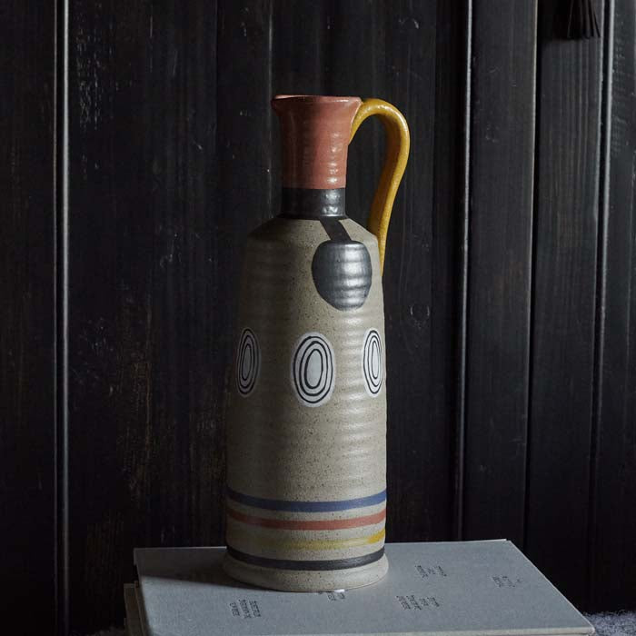 Patterned jug-shaped vase sat on a stack of books