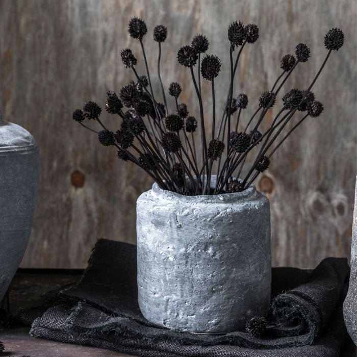 Styled image of a dried allium flower arrangement in a grey vase, from interior designer Abigail Ahern who specialises in fake flowers that look real.