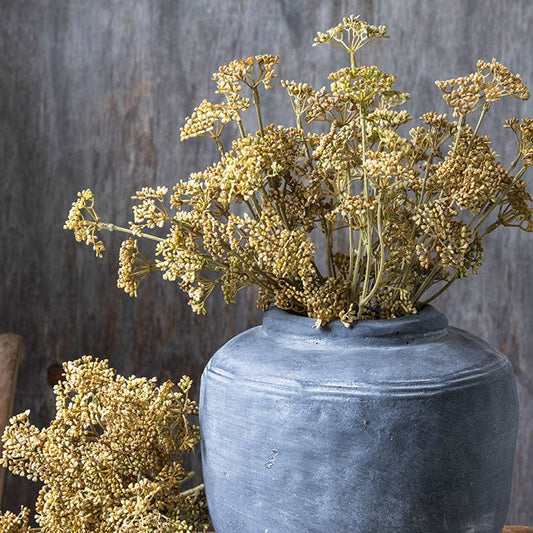 Grey stoneware vase filled with artificial meadow foliage.