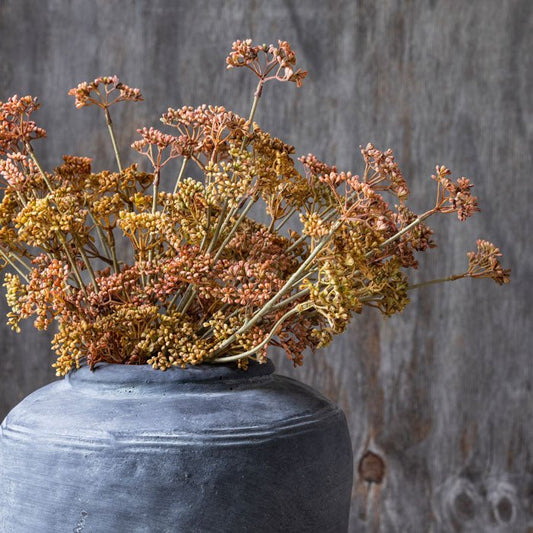 Artificial meadow foliage in orange tones, displayed in grey stoneware vase.
