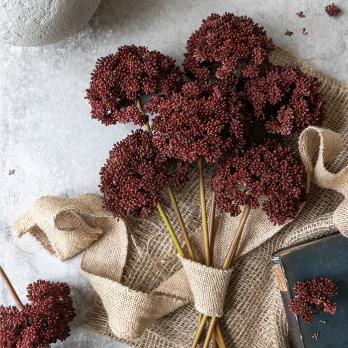 Six stems of artificial sedum foliage in crimson colour, tied with hessian fabric.