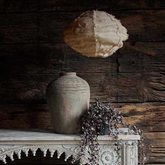 Drongo jute pendant fabric ceiling lampshade hung above a carved console with a trailing plant and a large oversized vase. 