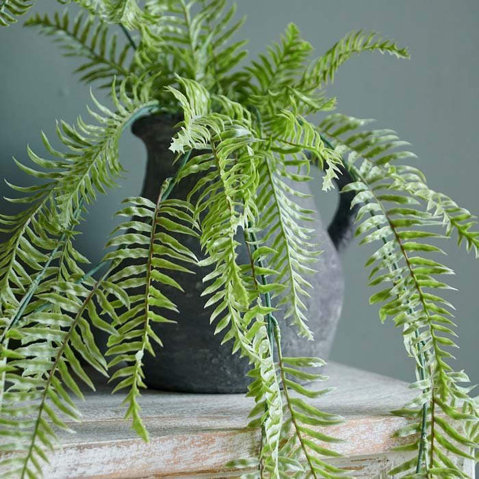 Close up image of a few stems of artificial ferns in a vibrant green colour.