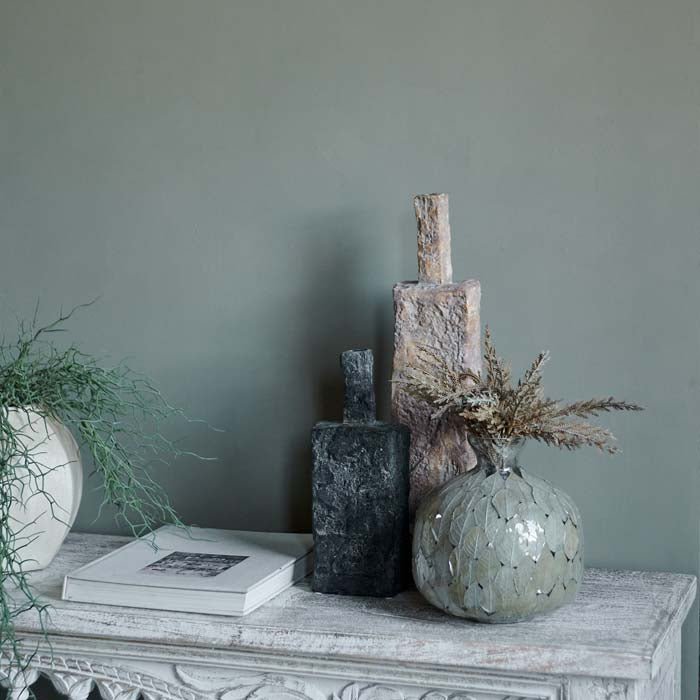 Woodstock is a lovely soft green paint colour has been styled behind a carved console with some rustic vases of different heights and contrasting colours. 