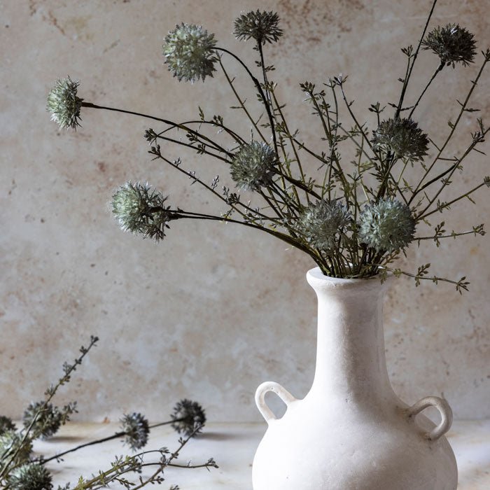 A fake flower bouquet made of several faux flower stems with very pale green spiky heads