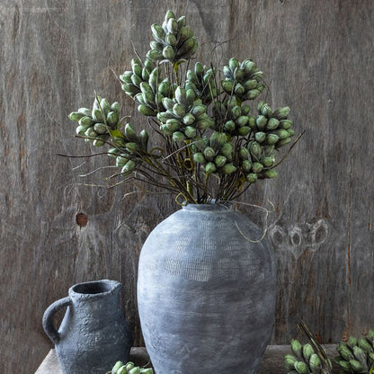 A large oversized vase filled with faux thistles. A realistic flower display that will look striking on a hallway console. Quality artificial flowers.