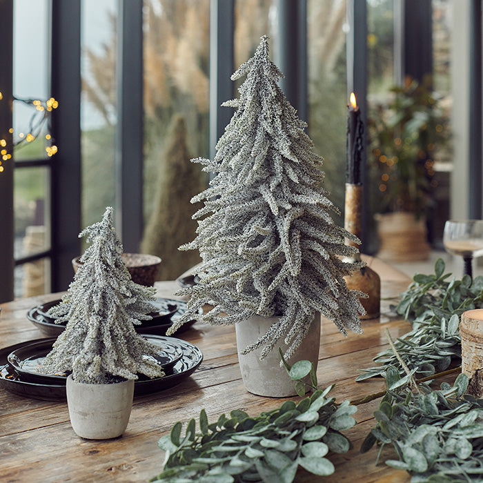An extra large life-like pine trees laid on a festive table spread.