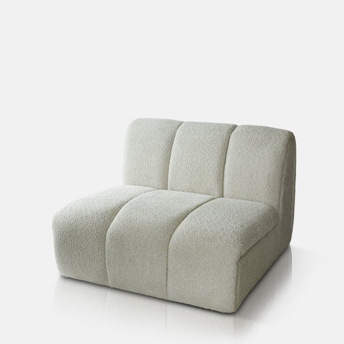 Cutout image on a white background of a large cream occasional chair, with no arms and three vertically stitched panels.