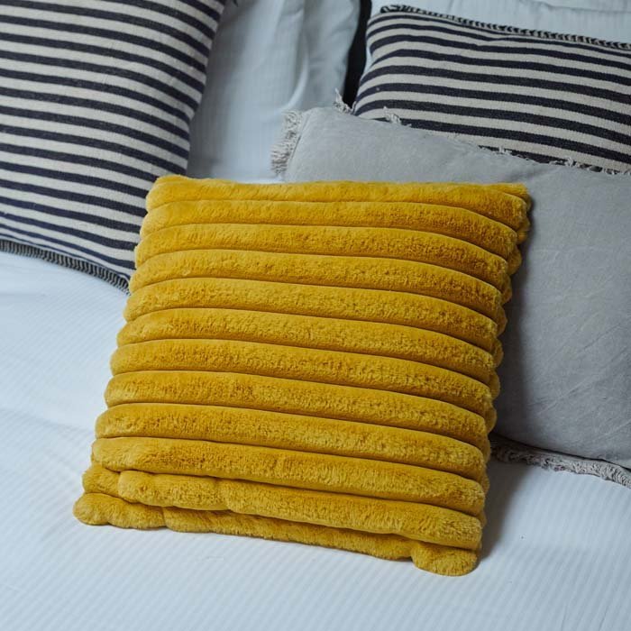 The Kinsley Cushion, a square cushion in vibrant mustard coloured faux fur with ridged detail.