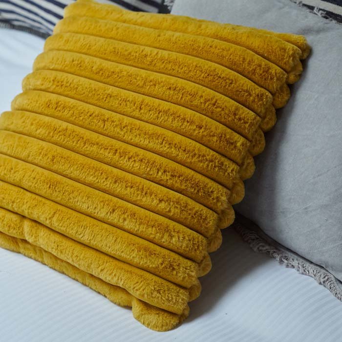 Yhe Kinsley Cushion, a square cushion in vibrant mustard coloured faux fur with ridged detail.