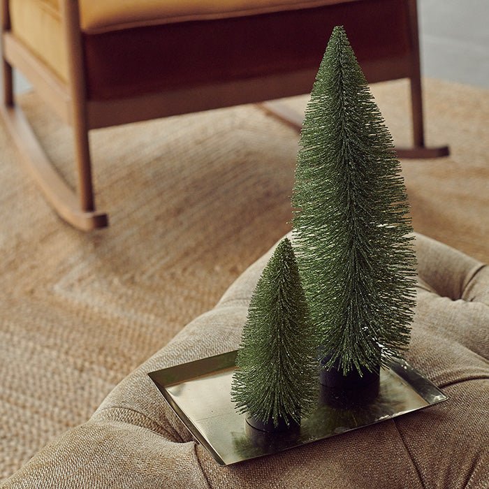 Two decorative fir trees laid on a sofa.