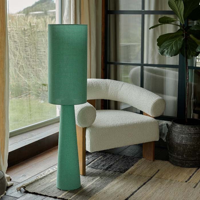 Rylan Floor Lamp - Green Gingham, a tall slim cylindrical floor lamp in green gingham fabric, next to a cream boucle chair.