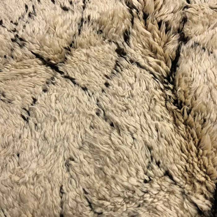 Close-up of a natural fibre rug in sandy tones with a diamond design.