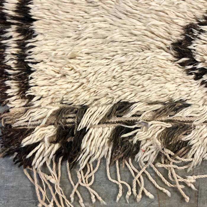 Natural fibre blend rug with tassels laid on the floor.