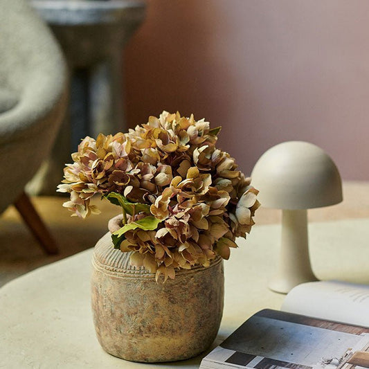  Maple is a pale soft blush pink colour perfect for creating an accent wall.Pink painted wall with a vase of faux hydrangeas an open book and a small domed table lamp.