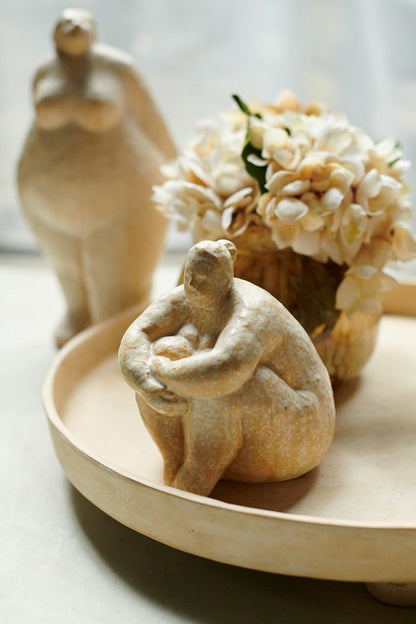Seated curvaceous female sculpture in a light cream colour way. Sculpture in a thoughtful pose to add a unique style to your home decor. 