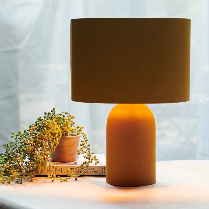 A yellow table lamp that's creating a warm glow next to a small faux plant.