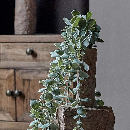 Detail shot of the faux trailing eucalyptus in a textural brown Emin vase. This versatile green fake plant is part of Abigail Ahern's premium homeware collection.