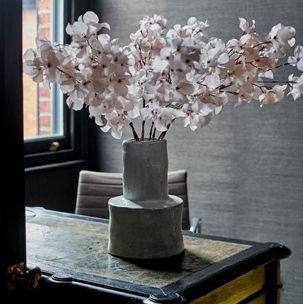 The Bremen Vase - Large, a glossy white stoneware vase with a chunky cylindrical base and a rustic feel, with faux florals.