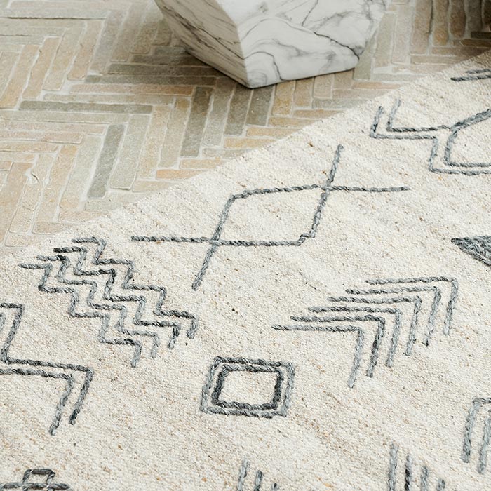 A closeup of the Tampa Wool Rug, a cream rug with a beautiful black pattern in chevron style designs.